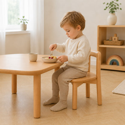 Kleiner Junge sitzt auf einem Montessori Kinderstuhl beim Essen