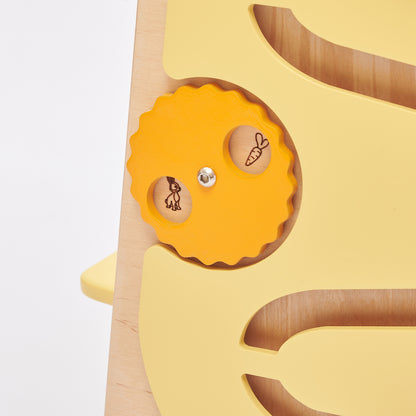 Montessori Lernturm aus Naturholz mit gelbem seitlichem Busy Board, ausgestattet mit interaktiven Zahnrädern, Schiebereglern und verschließbaren Elementen für Kleinkinder.